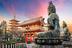 Traditional Japanese temple with pagoda and Buddha statues at sunset in Tokyo.
