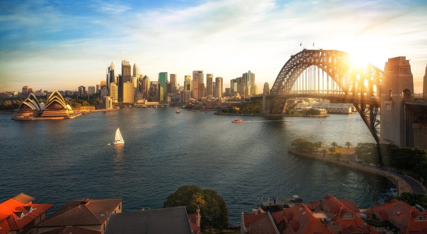 Sydney Harbour at sunset showing the Opera House, Harbour Bridge, and city skyline.