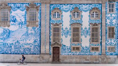 Blue and white azulejo-tiled church facade with a cyclist passing by in Porto, Portugal.