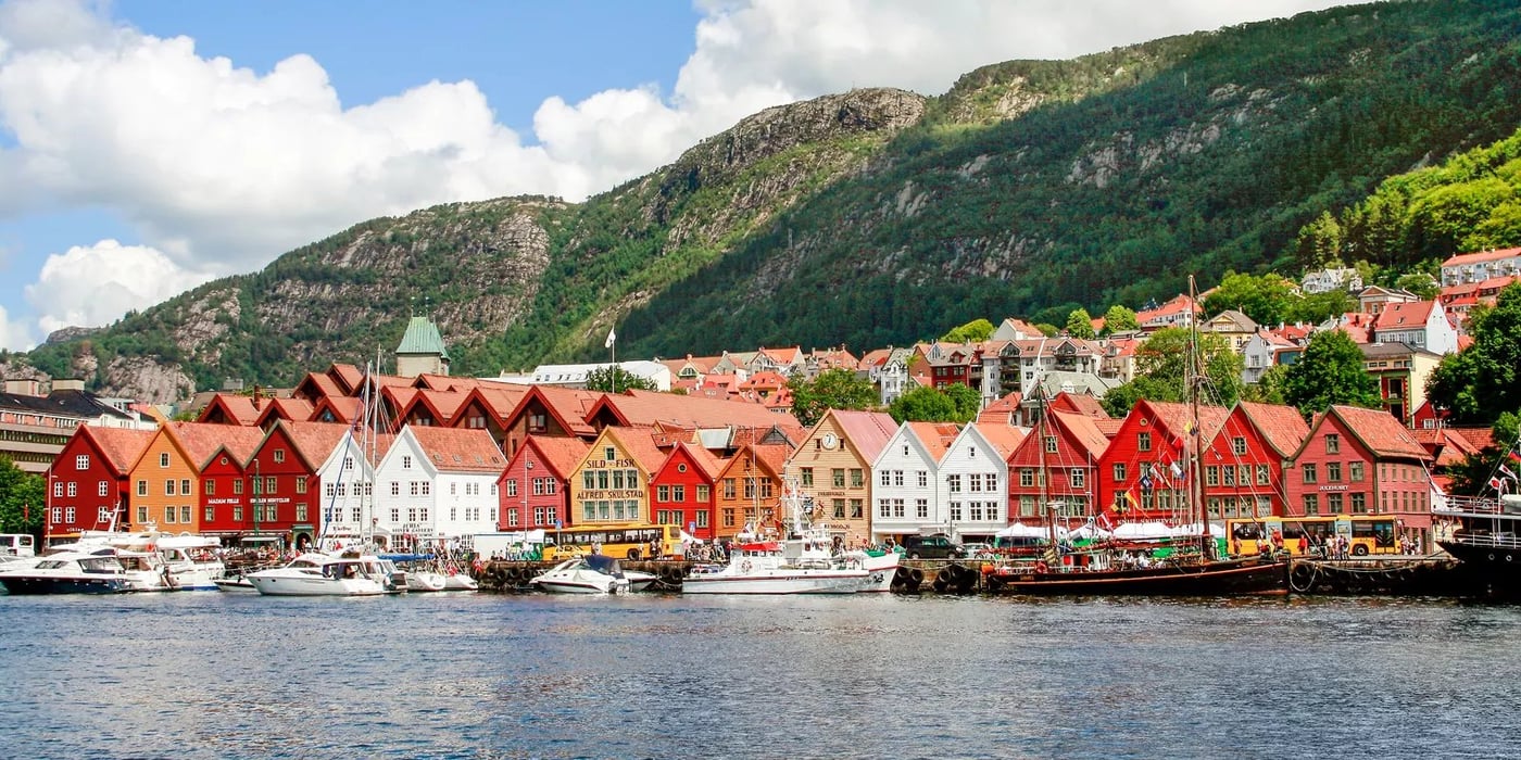 Colorful wooden buildings and boats along the historic Bryggen wharf in Bergen, Norway.