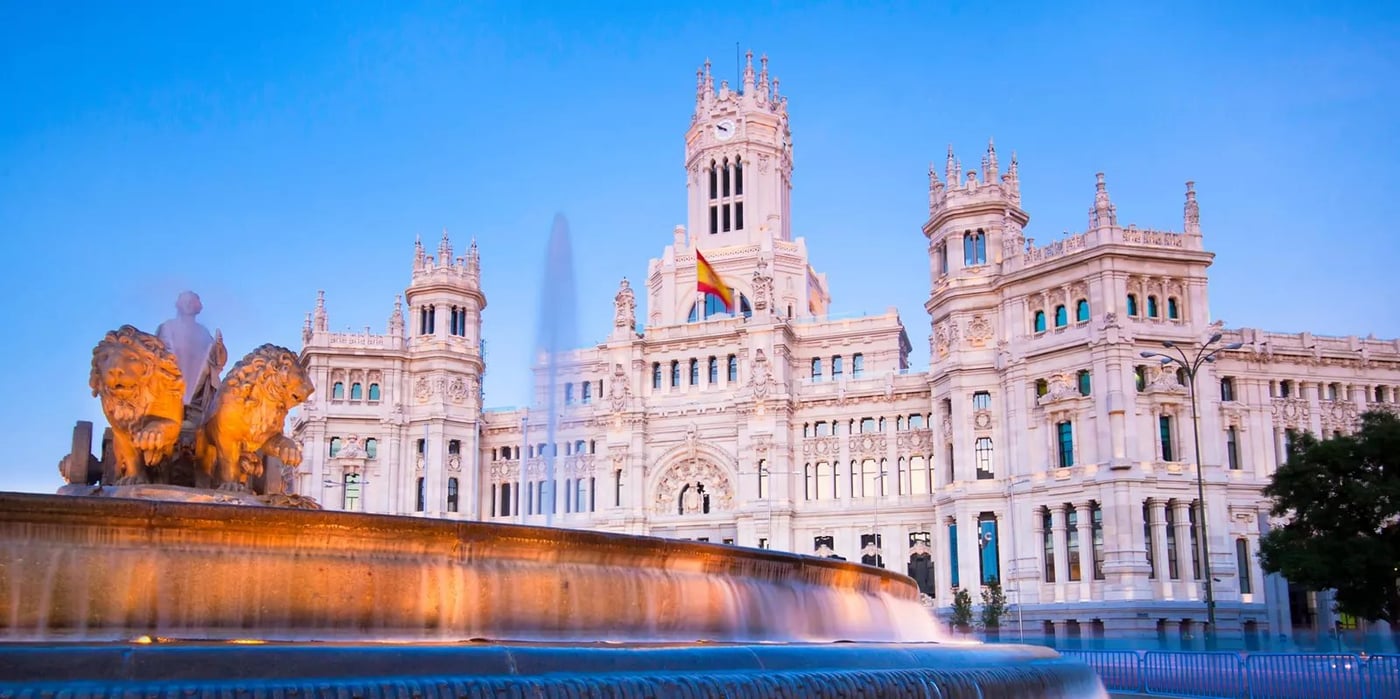 Palacio de Cibeles illuminated at twilight with fountain in foreground in Madrid, Spain.