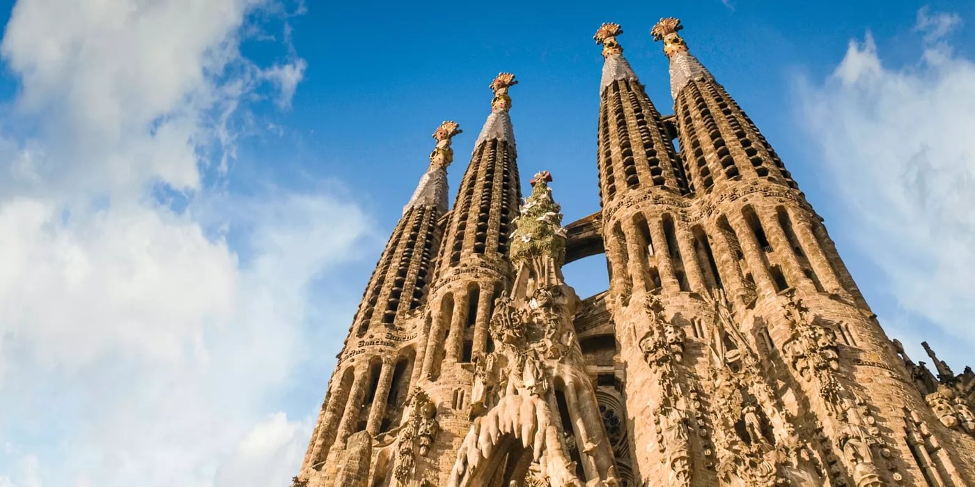 Sagrada Familia's ornate spires reaching skyward against blue sky in Barcelona, Spain.
