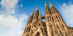 Sagrada Familia's ornate spires reaching skyward against blue sky in Barcelona, Spain.