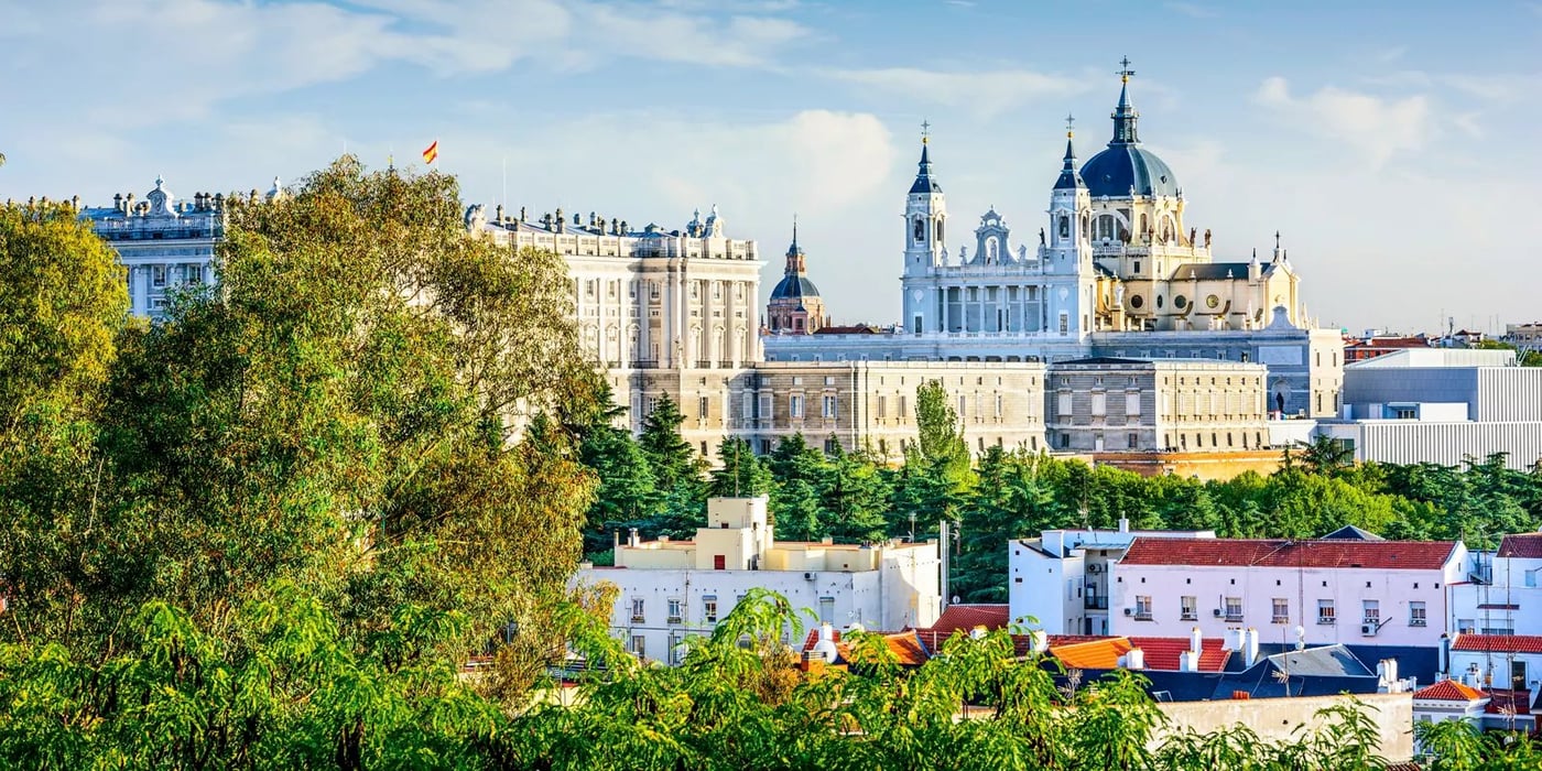 Almudena Cathedral and Royal Palace rising above green parkland in Madrid, Spain.