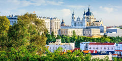 Almudena Cathedral and Royal Palace rising above green parkland in Madrid, Spain.