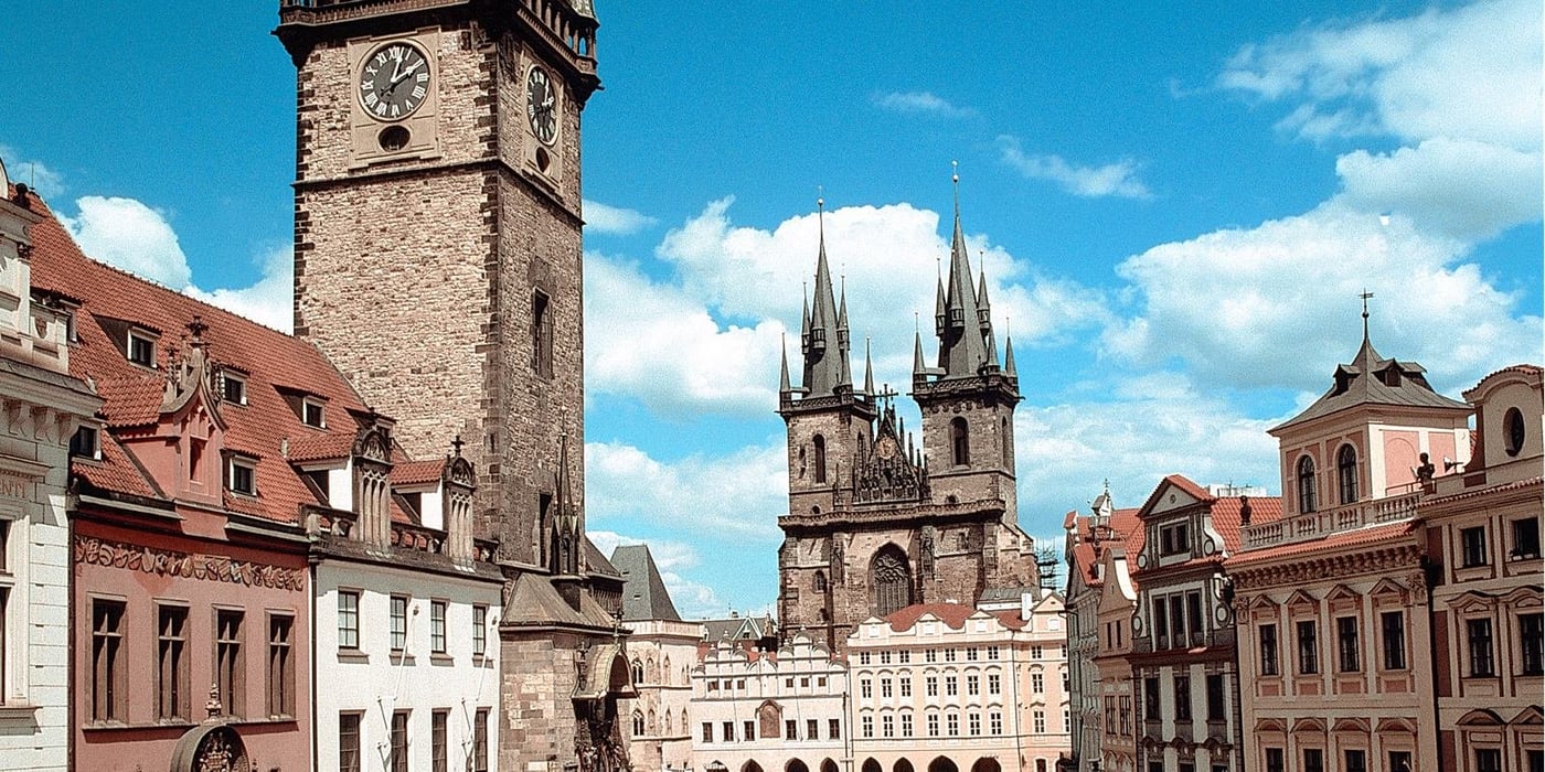 Prague Old Town Square showing the Astronomical Clock tower and Church of Our Lady before Týn under blue sky.