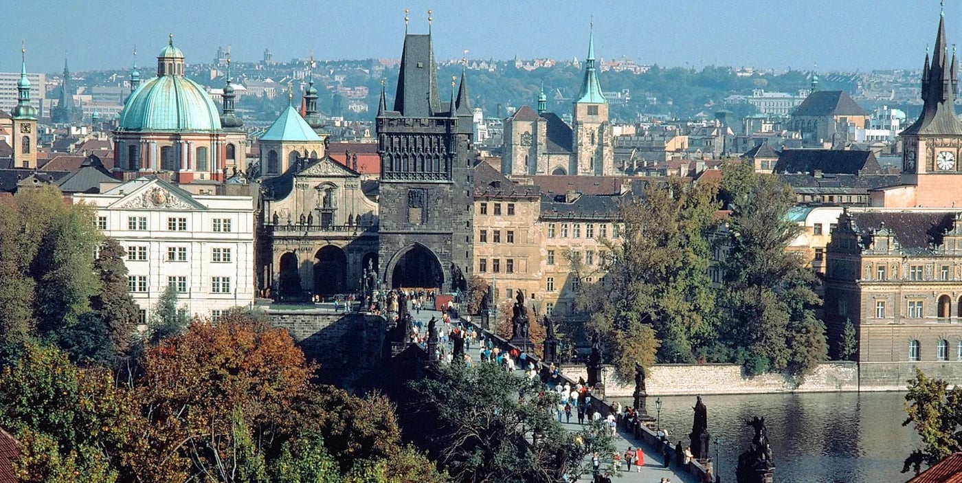Aerial view of Prague showing Charles Bridge and the historic city center with church domes and towers.