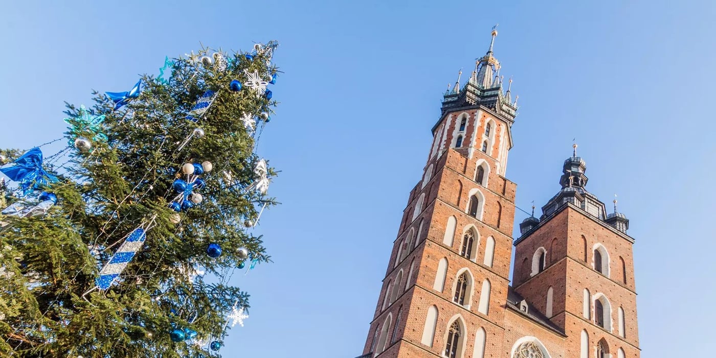 Twin towers of St. Mary's Basilica in Krakow photographed from below with tree foliage in the foreground.