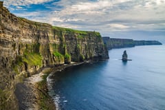 The Cliffs of Moher stretching along the Atlantic coast with dramatic sea stacks and layered rock faces.