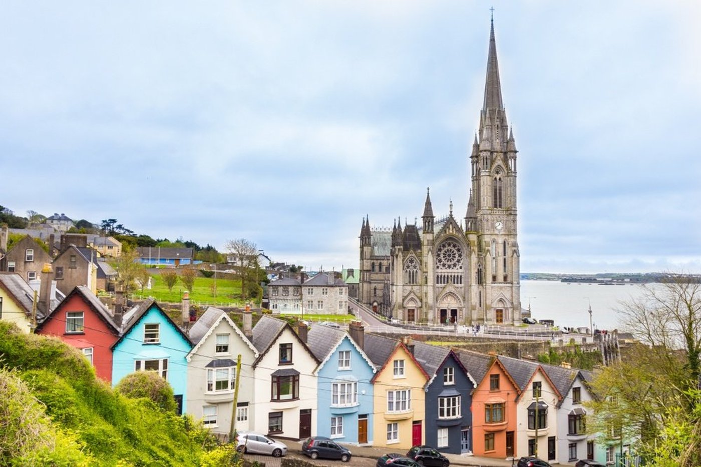 Cobh Cathedral rising above a row of colorful Victorian houses along the Irish waterfront.