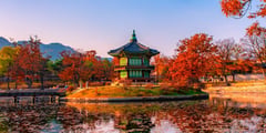 Traditional Korean pavilion reflected in a pond surrounded by autumn foliage at Gyeongbokgung Palace in Seoul.