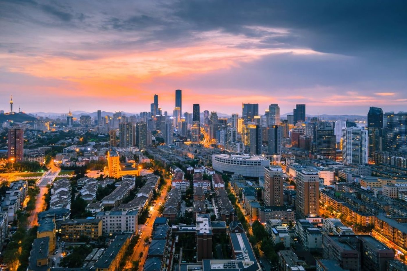 Aerial view of Beijing's illuminated cityscape at dusk with modern skyscrapers.