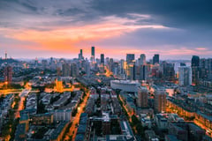Aerial view of Beijing's illuminated cityscape at dusk with modern skyscrapers.