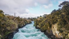 Turquoise rapids flowing through a narrow river gorge surrounded by native bush.