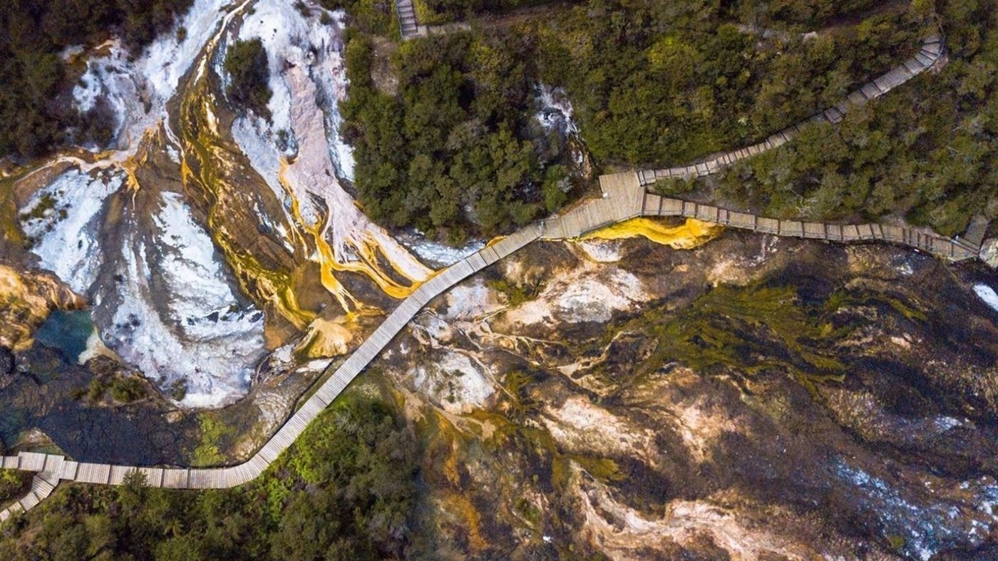 Aerial view of wooden boardwalks winding through a geothermal or limestone landscape.