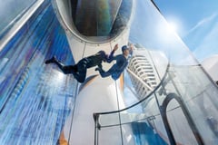 Passengers experiencing a skydiving simulator attraction on the cruise ship.
