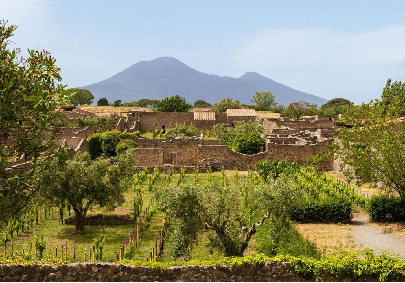 Ancient ruins at Pompeii with Mount Vesuvius visible in the background under clear skies.