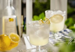 Glasses of limoncello cocktail with ice and lemon garnish on a table.